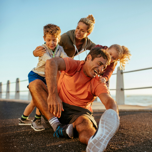 A man is laying on the ground with two children on his back.