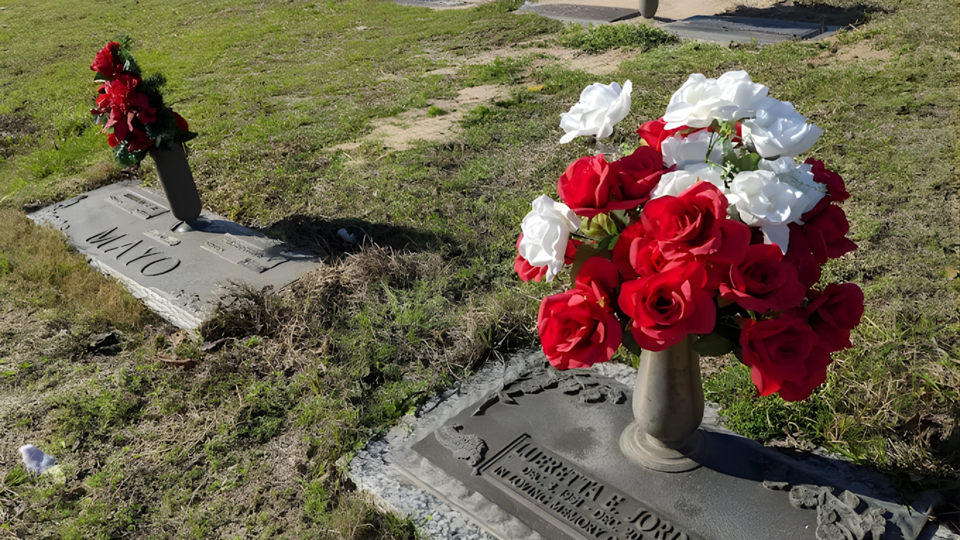 Flowers lie on a stone headstone in a cemetery.