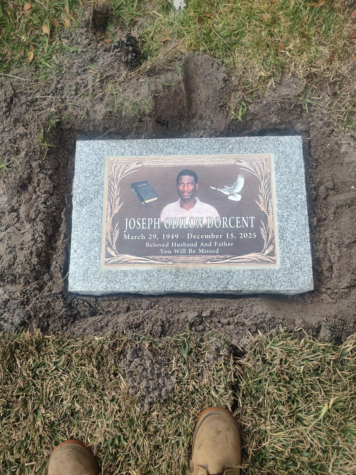 Grave marker with photo of a man; set in dirt and grass.
