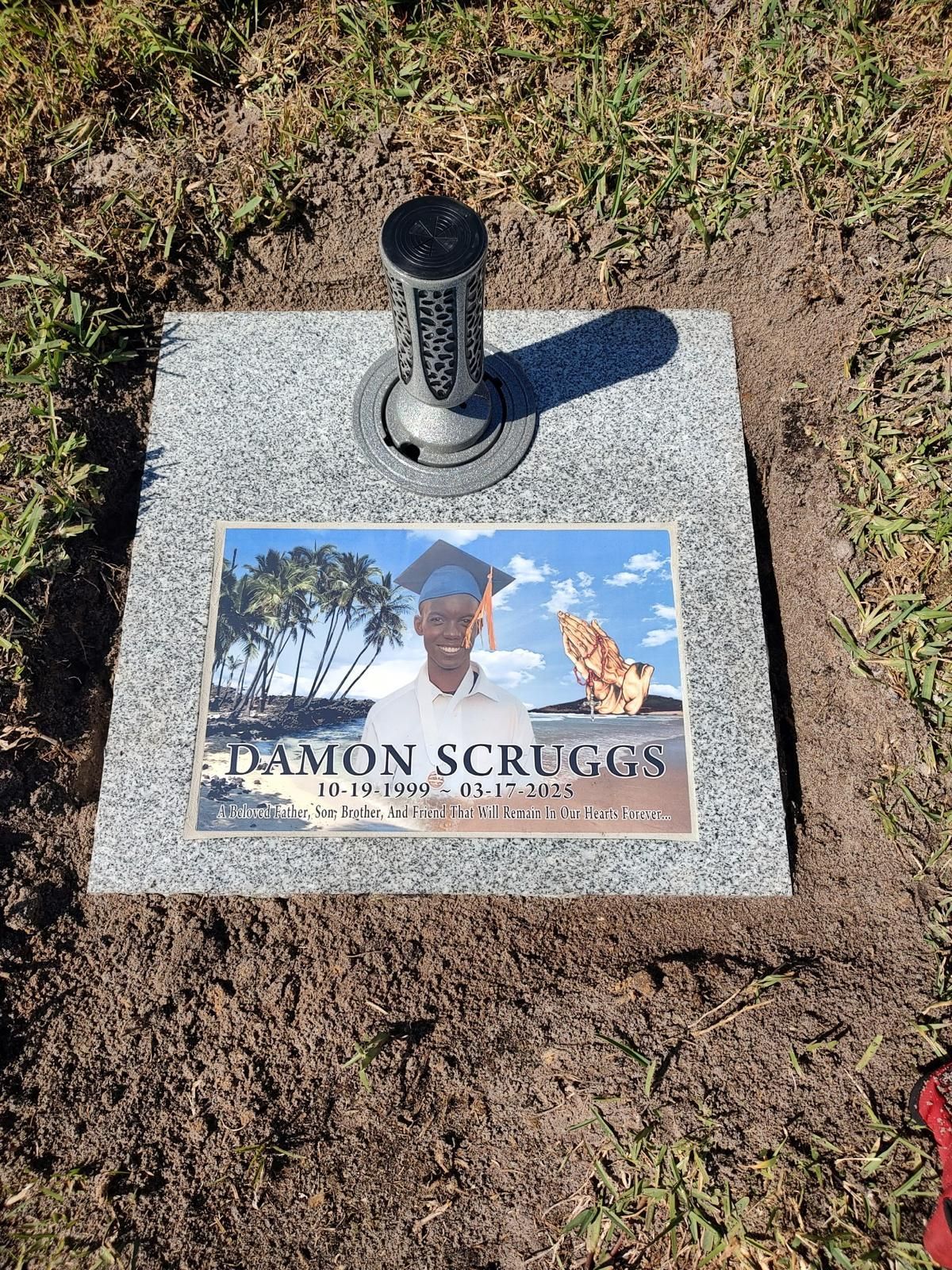 Gravestone with photo of Damon Scruggs, a young man, set in a cemetery plot.