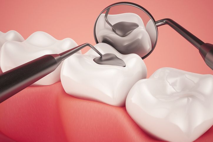 Dental tools examining a white tooth with a mirror and probe on a pink background