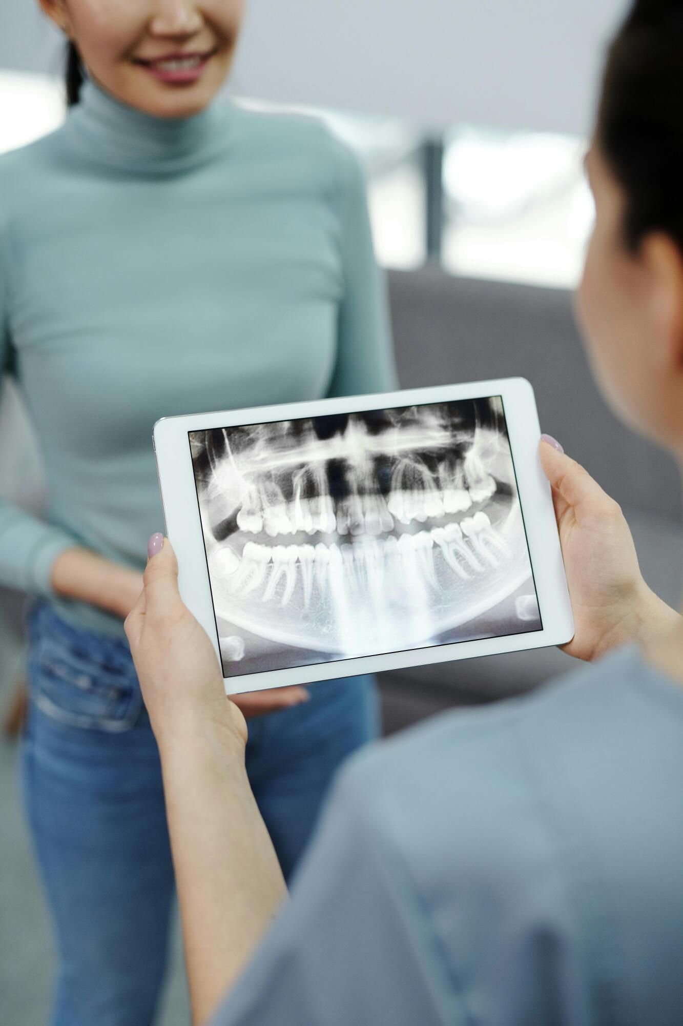 Dentist showing a panoramic dental X-ray on a tablet to a patient in a clinic