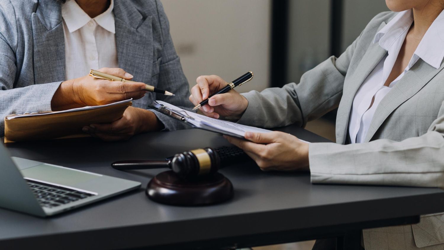 Two business people discussing a contract over a laptop with a gavel on the table