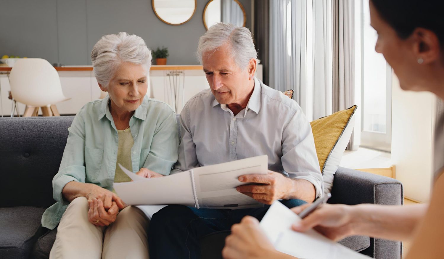 Two people reviewing documents on a couch while speaking with a seated counselor in a bright room