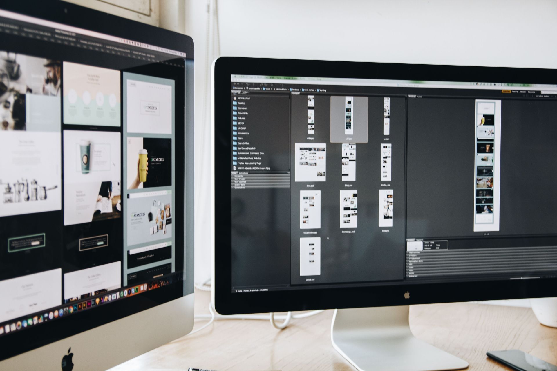 Two desktop monitors showing design or web layout mockups on a desk