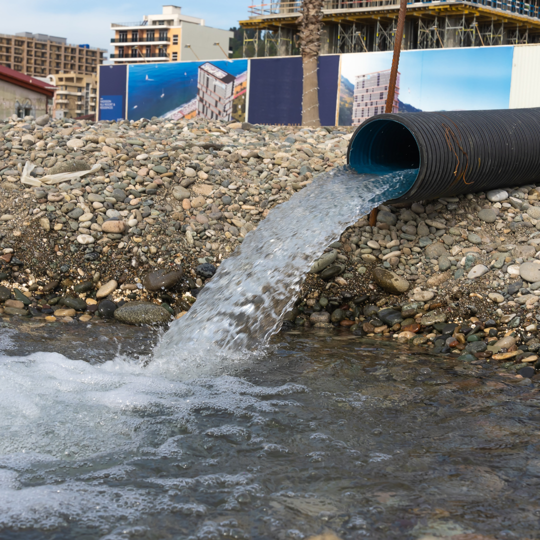A large pipe is pouring water into a river