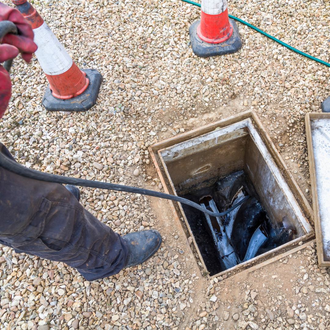 A man is cleaning a drain with a hose.