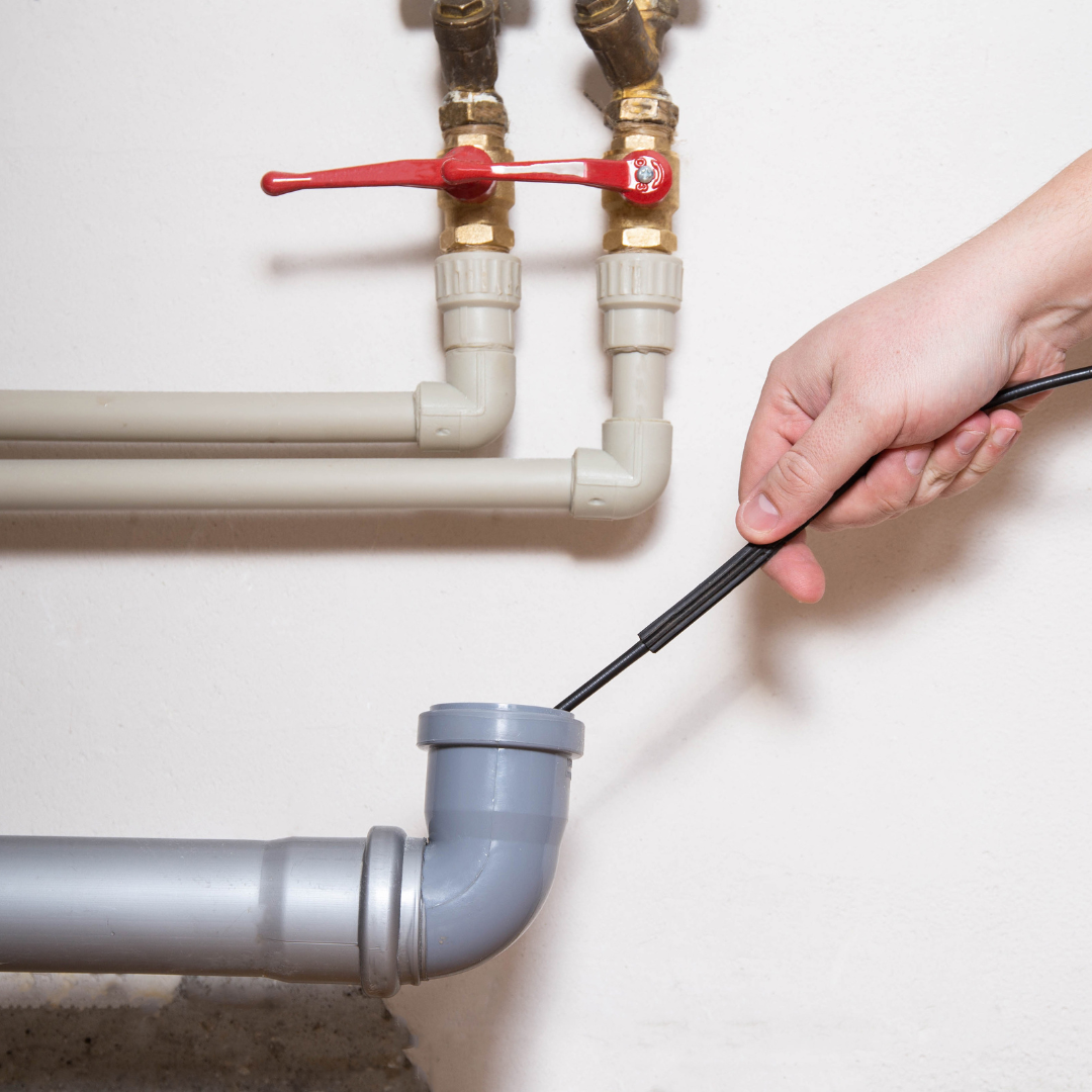A person is cleaning a pipe with a hose.