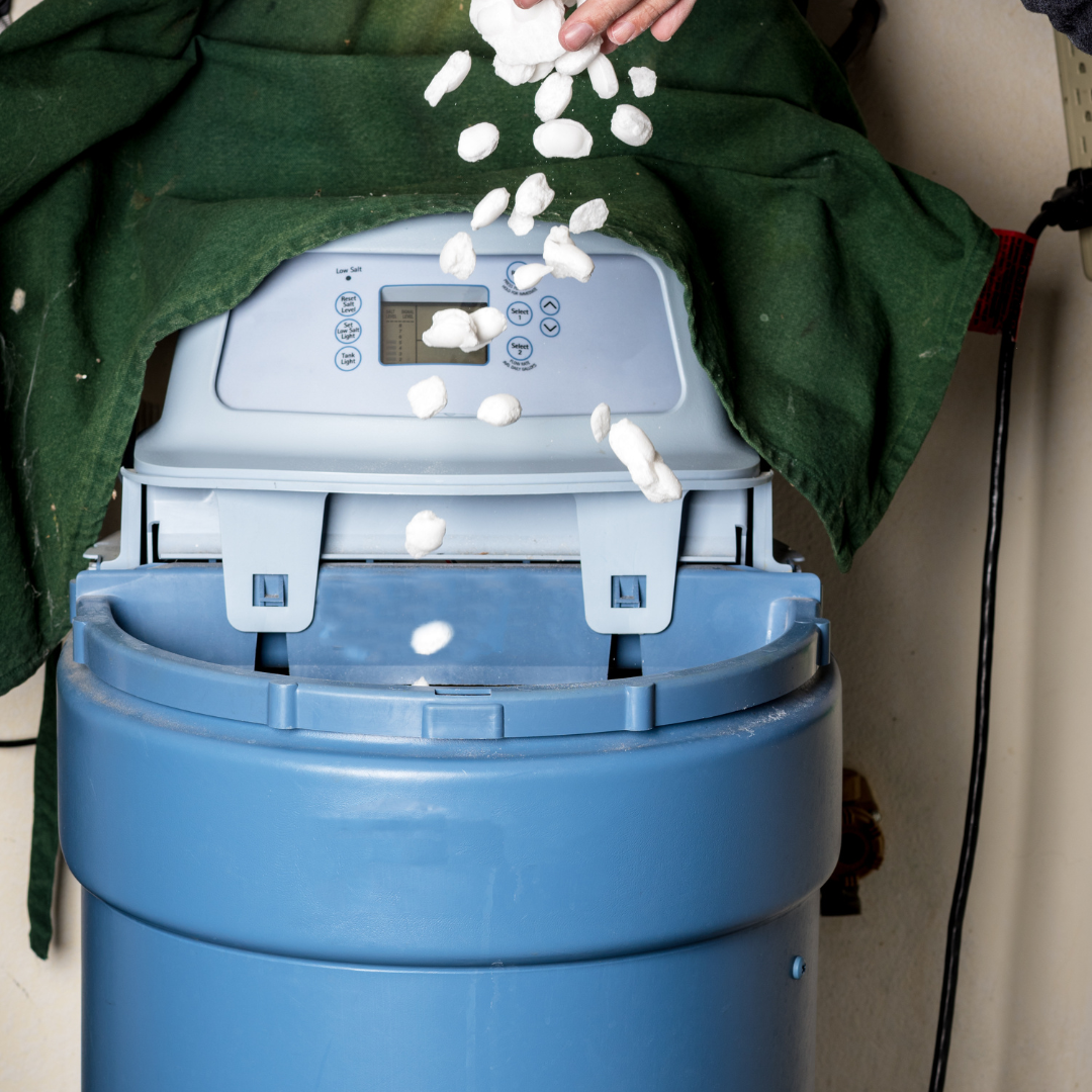 A person is pouring salt into a water softener