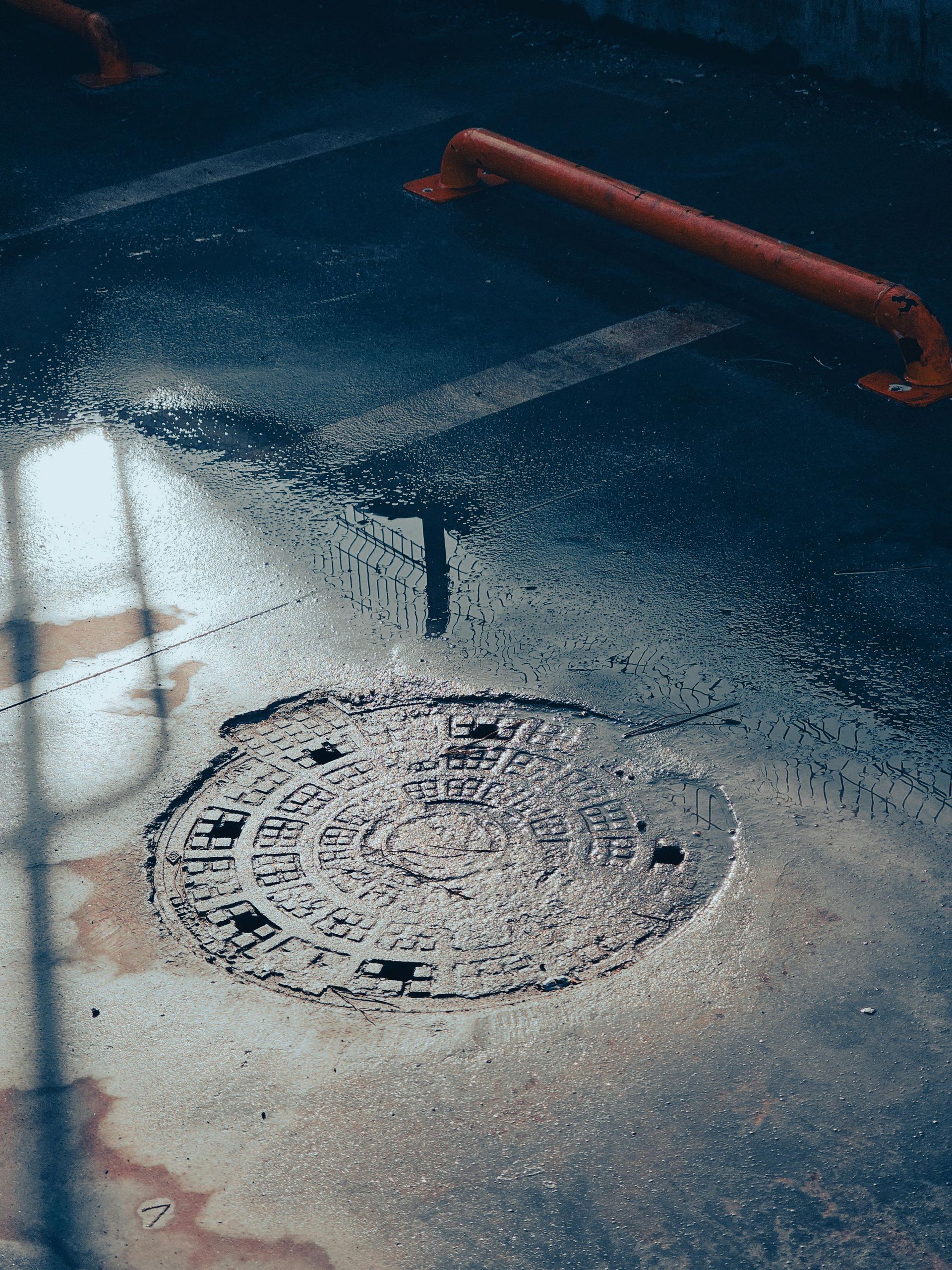 A manhole cover is sitting on the side of a wet road.