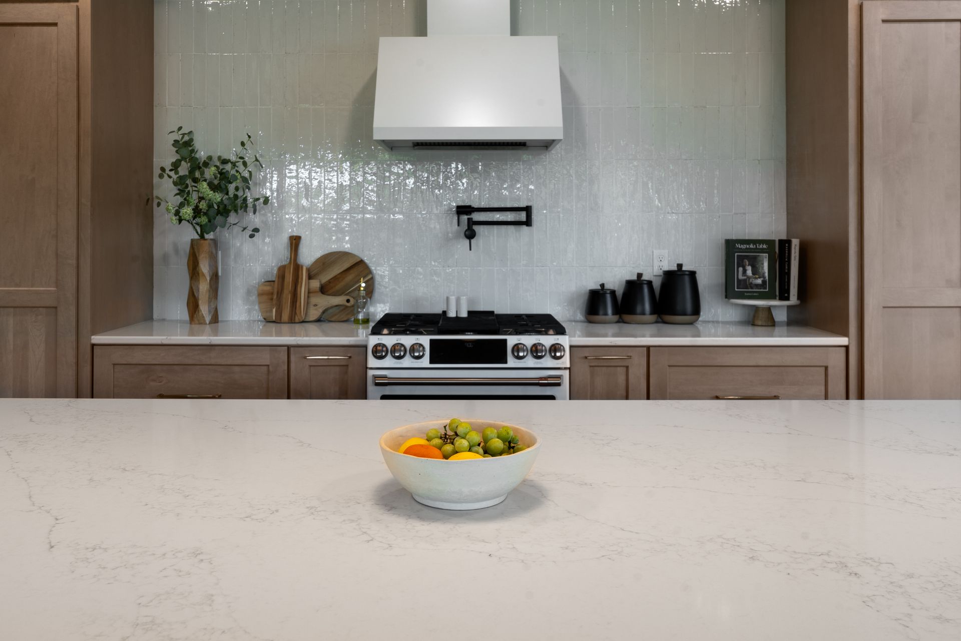 A kitchen with a large island and wicker chairs.