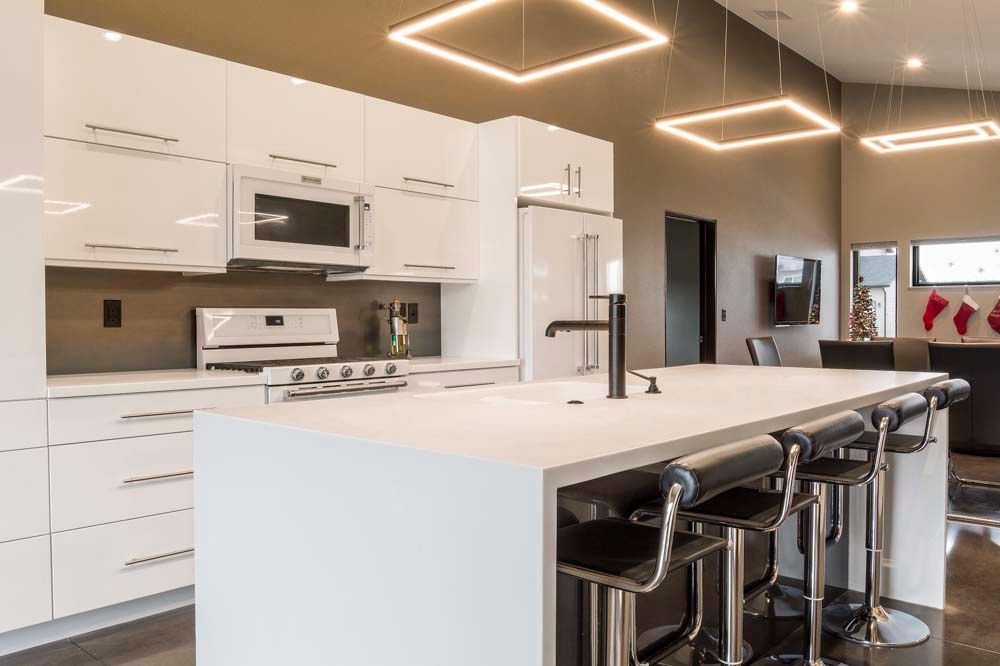 A kitchen with white cabinets , a large island , and stools.