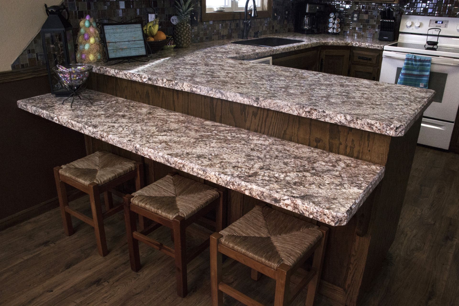 A kitchen with granite counter tops and wooden stools.