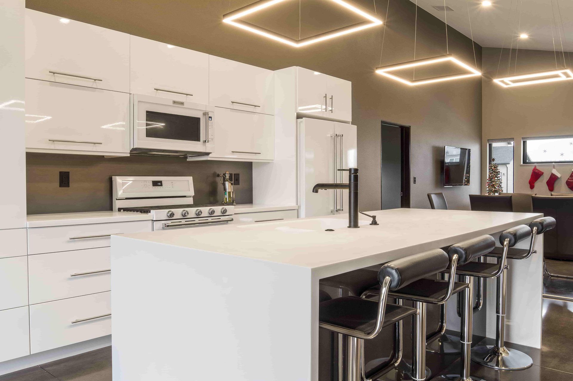 A kitchen with white cabinets , a large island , and stools.