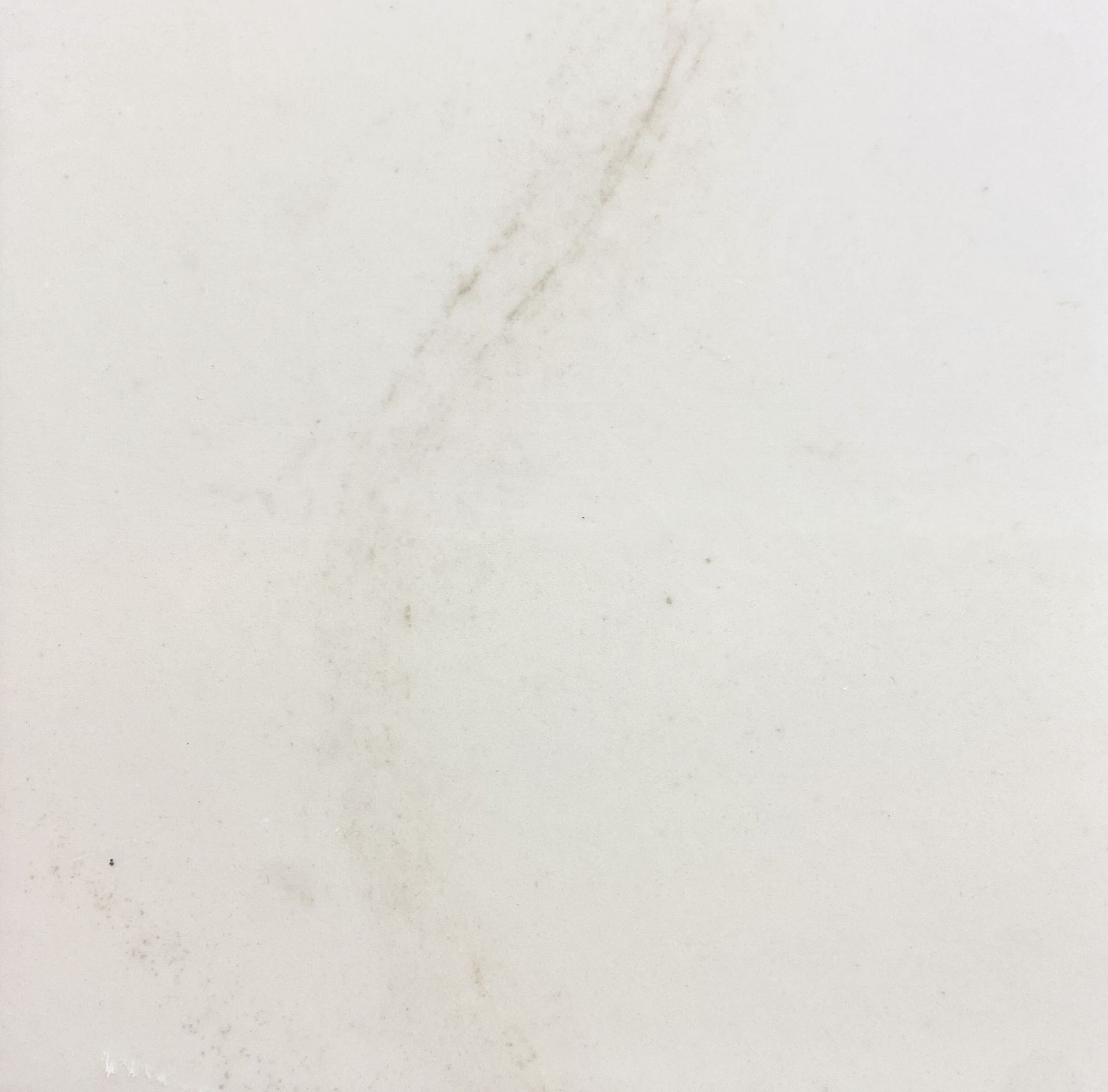 A close up of a white tile with a marble texture.