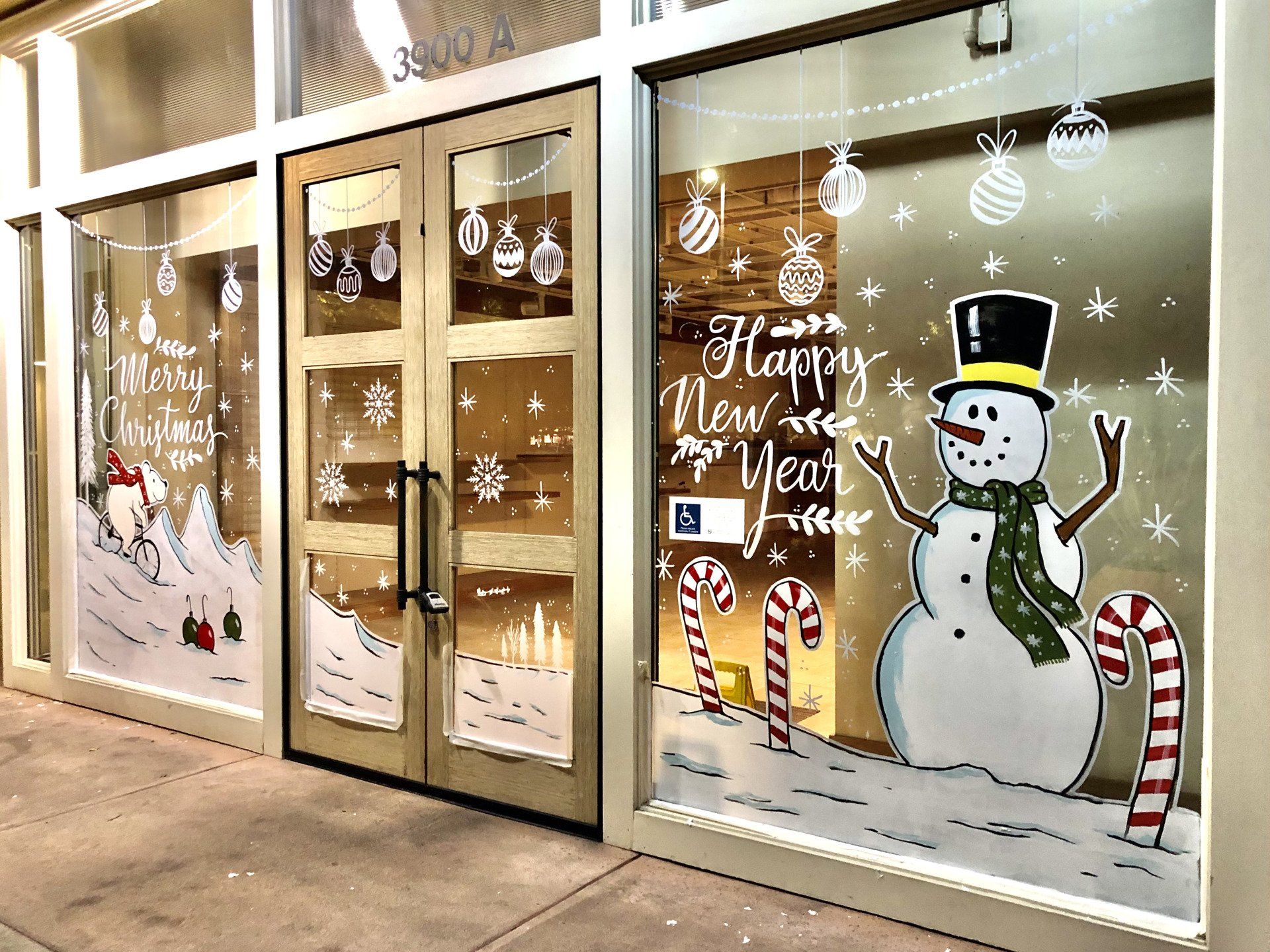 A store front with a snowman and candy canes painted on the windows.