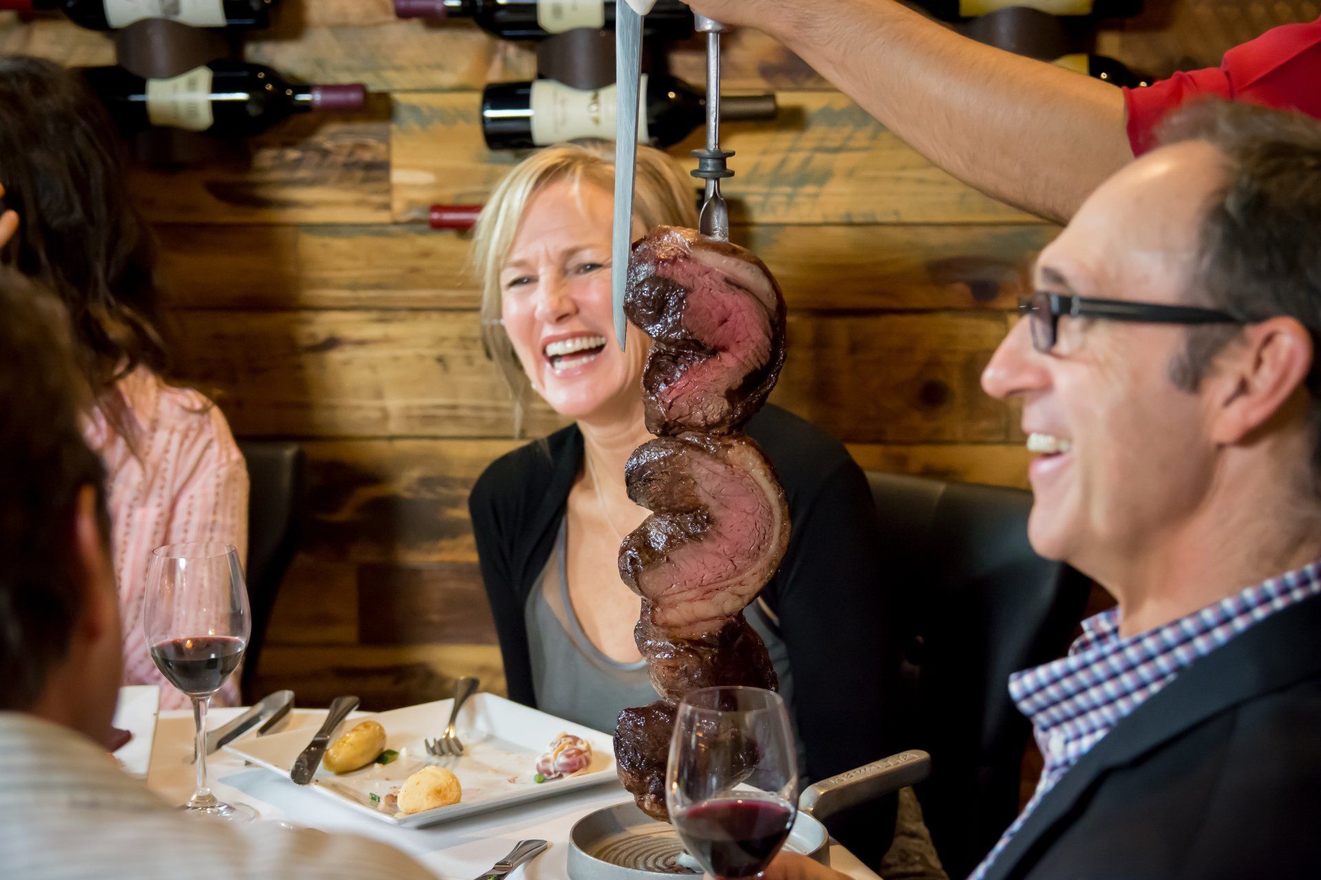 A group of people are sitting at a table eating food and drinking wine.