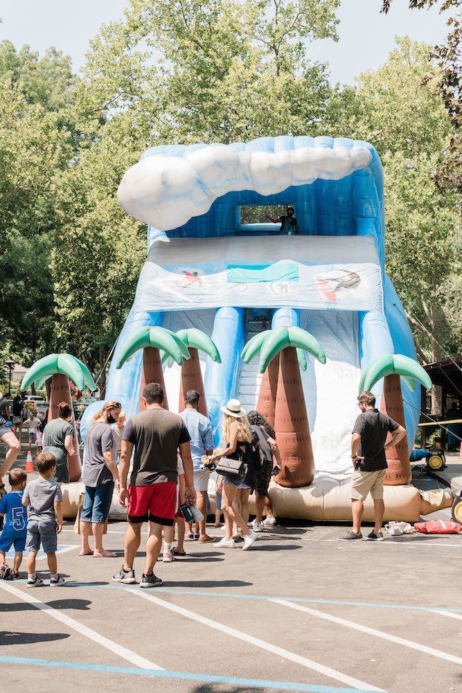 A group of people are standing in front of an inflatable water slide.