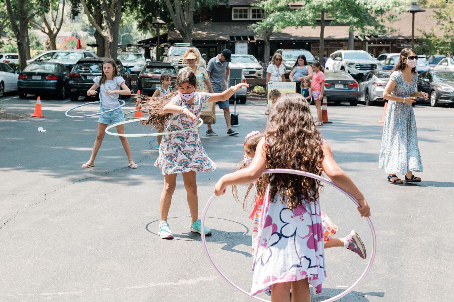 A group of young girls are playing with hula hoops in a parking lot.