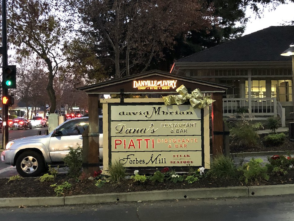 A white suv is parked in front of a sign that says david morton