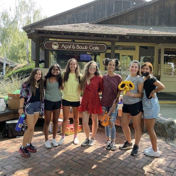 A group of young women are posing for a picture in front of the acai & bowl cafe