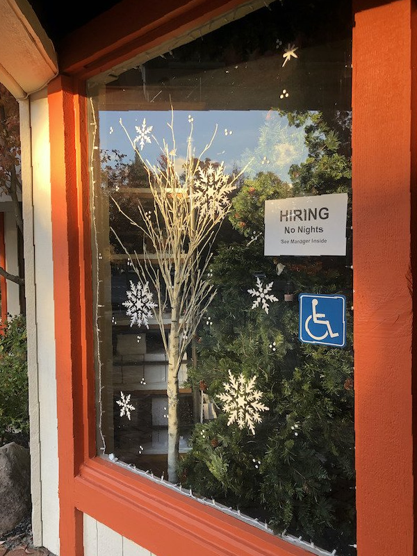 A window with a sign that says hiring on it
