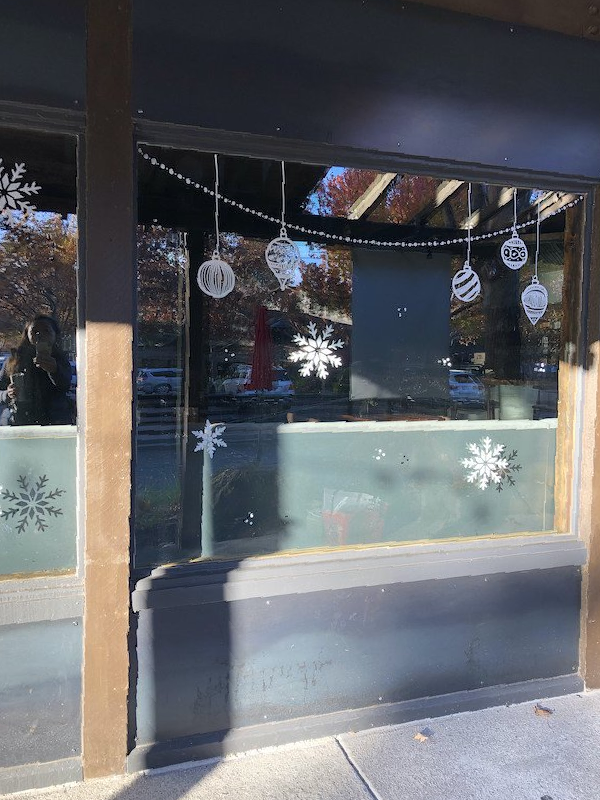 A store front with christmas decorations on the windows.