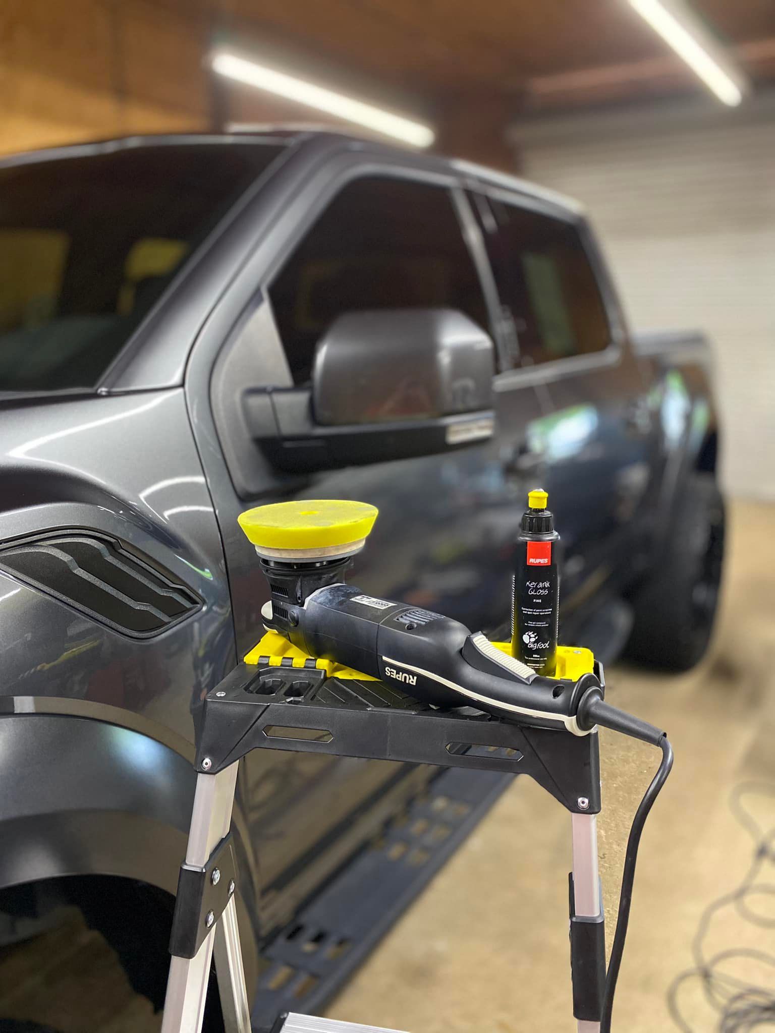 A gray truck is being polished in a garage.
