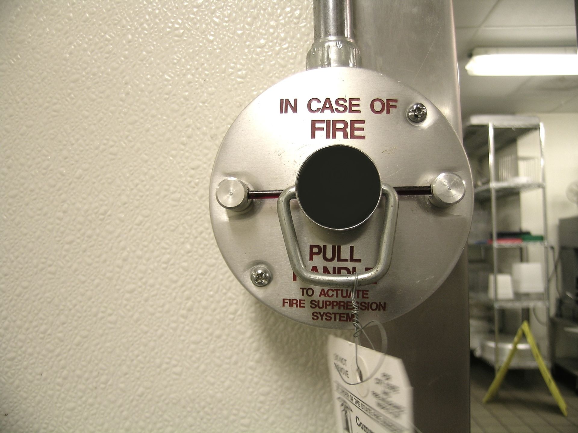 Close-up of a manual fire suppression system activation handle mounted on a metal panel.