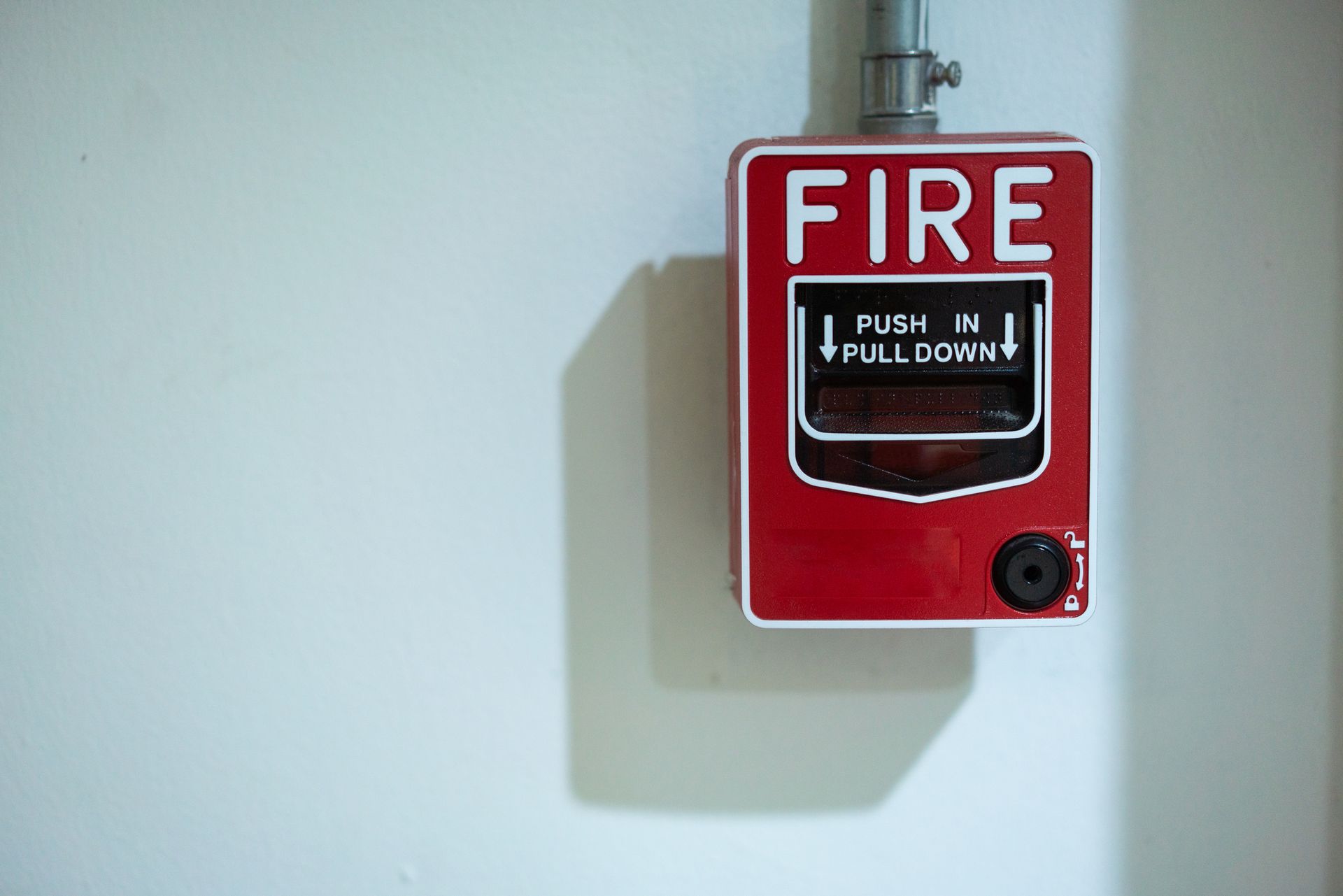 Wall-mounted red fire alarm system with emergency pull handle.
