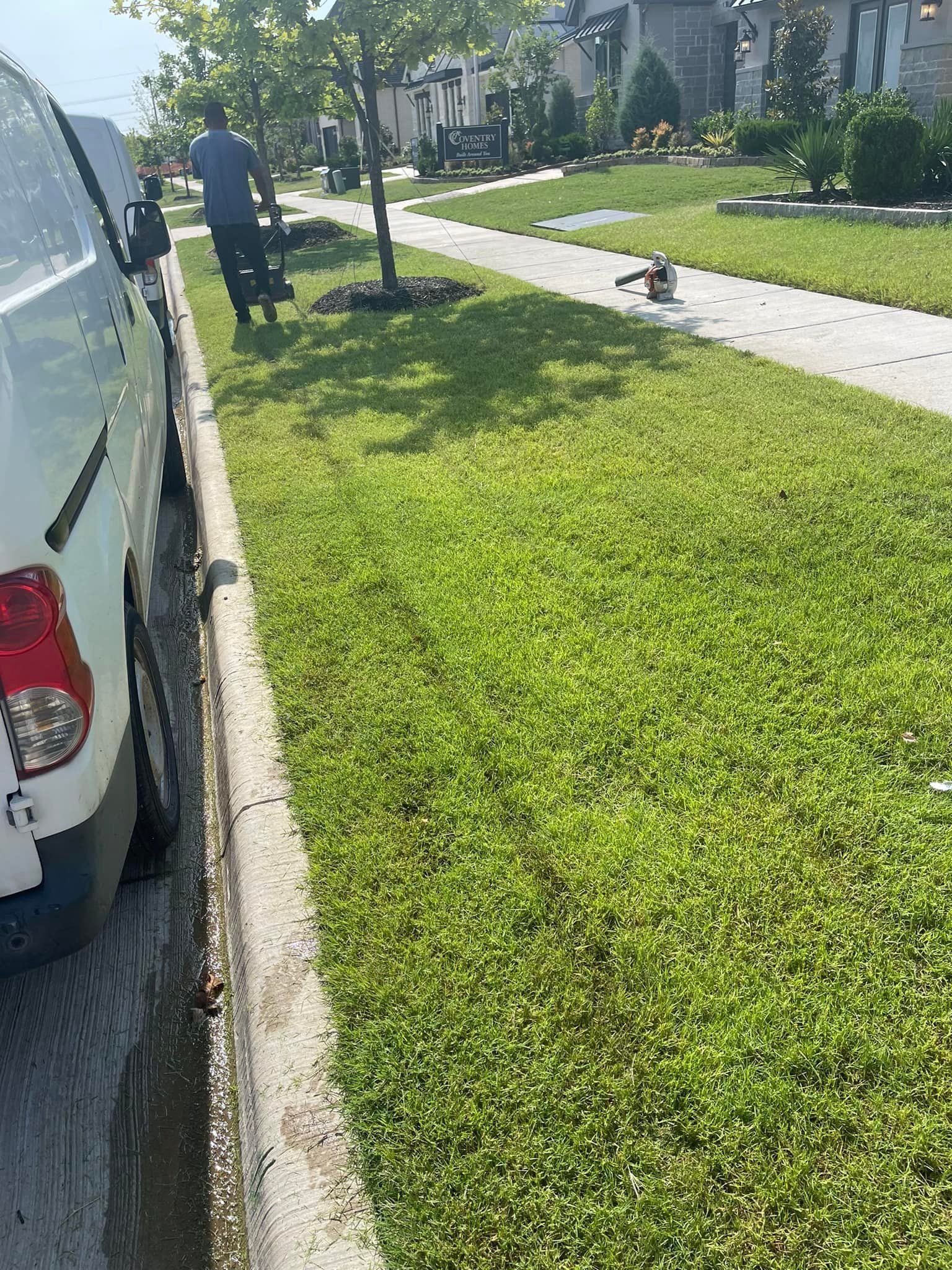 A white truck is parked on the side of the road next to a lush green lawn.