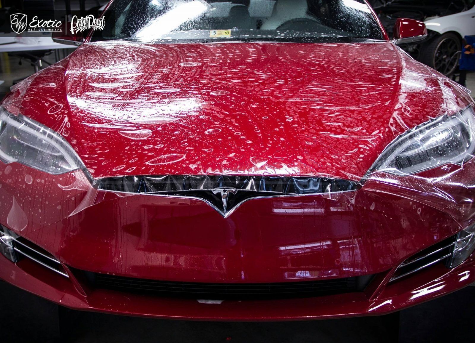 Red Tesla car with water droplets on the hood.