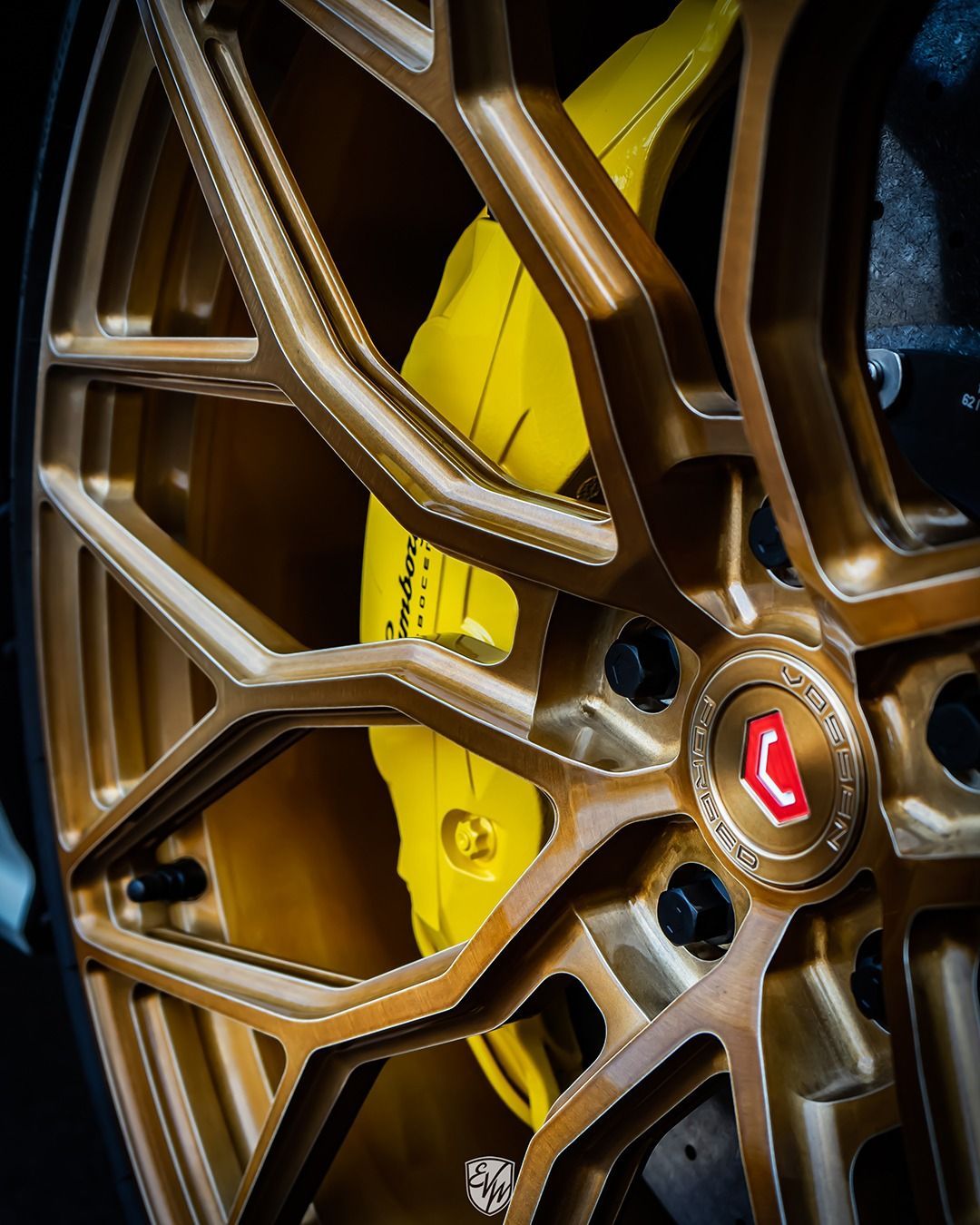 Gold car wheel with yellow brake caliper; close-up.