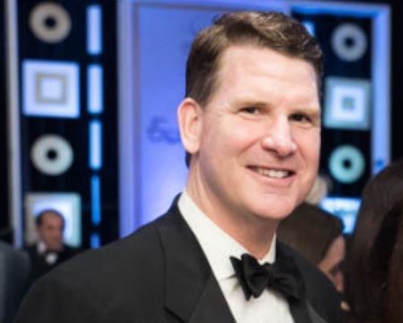 Sean. P. Murphy in a tuxedo smiles at the camera at a formal event.