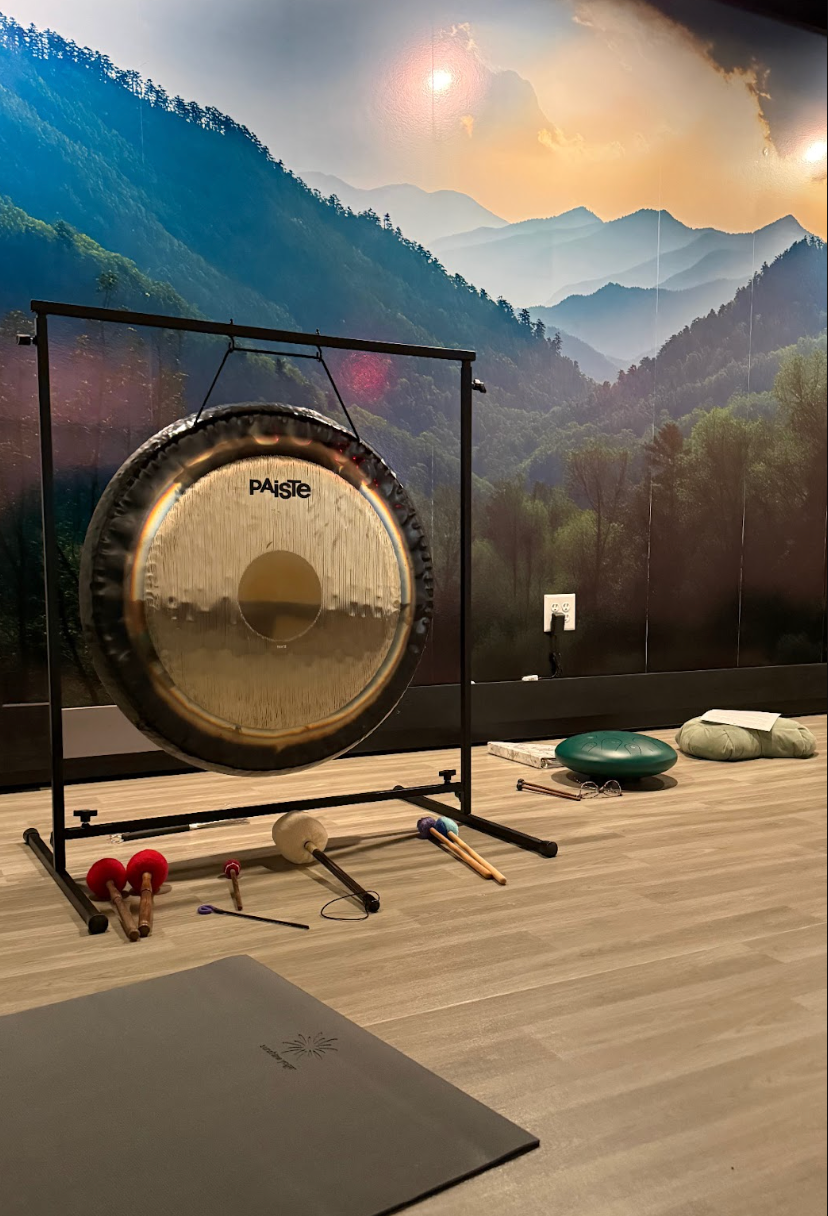 Woman plays crystal singing bowls, indoors. White top, red bracelet.