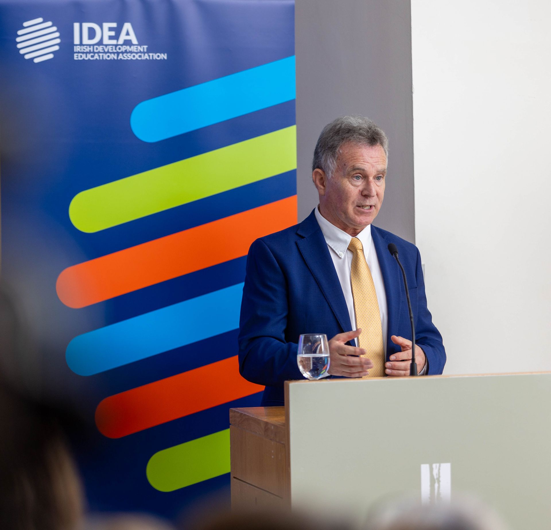 a man stands at a podium in front of an idea banner