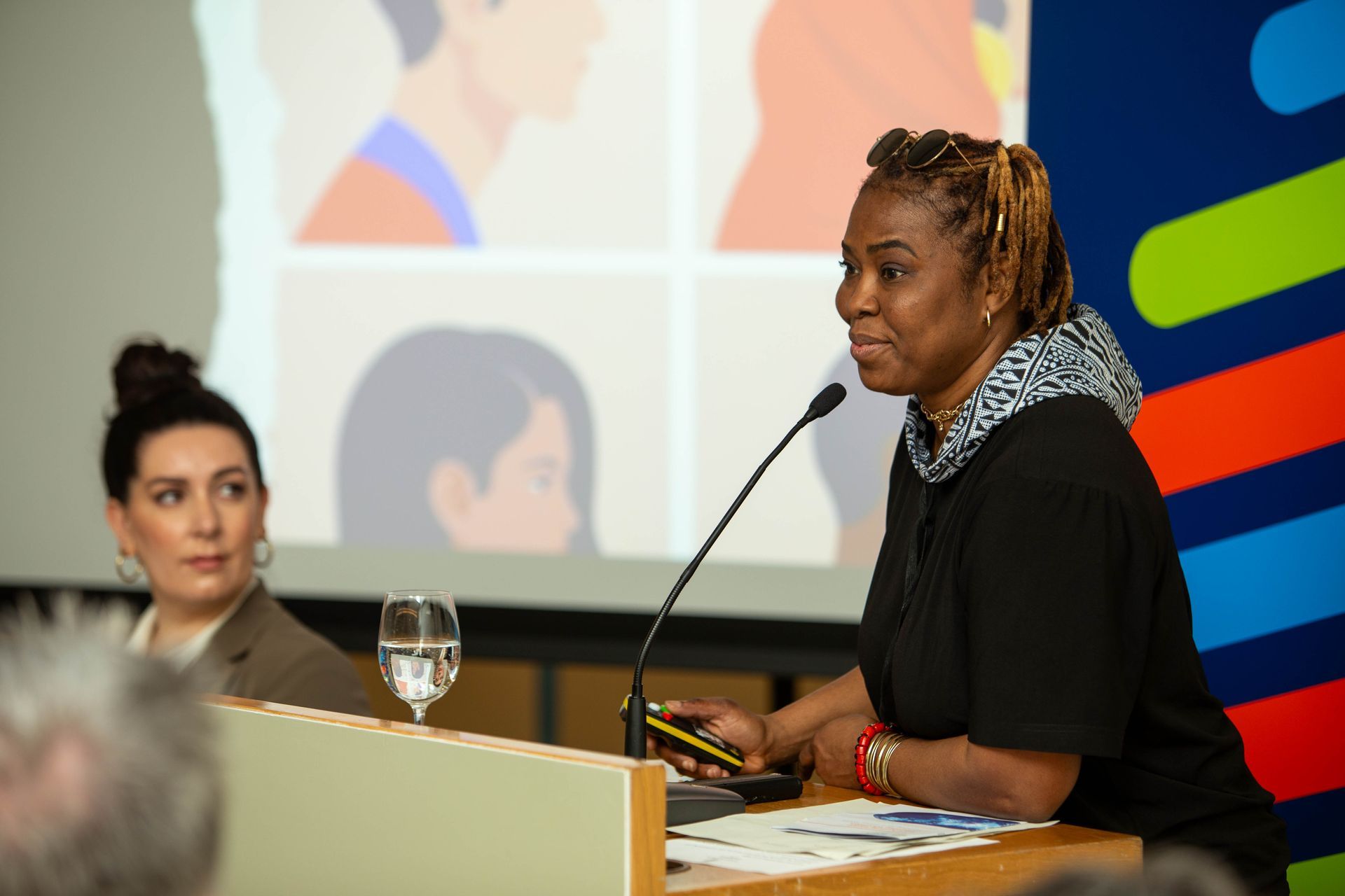a woman stands at a podium speaking into a microphone