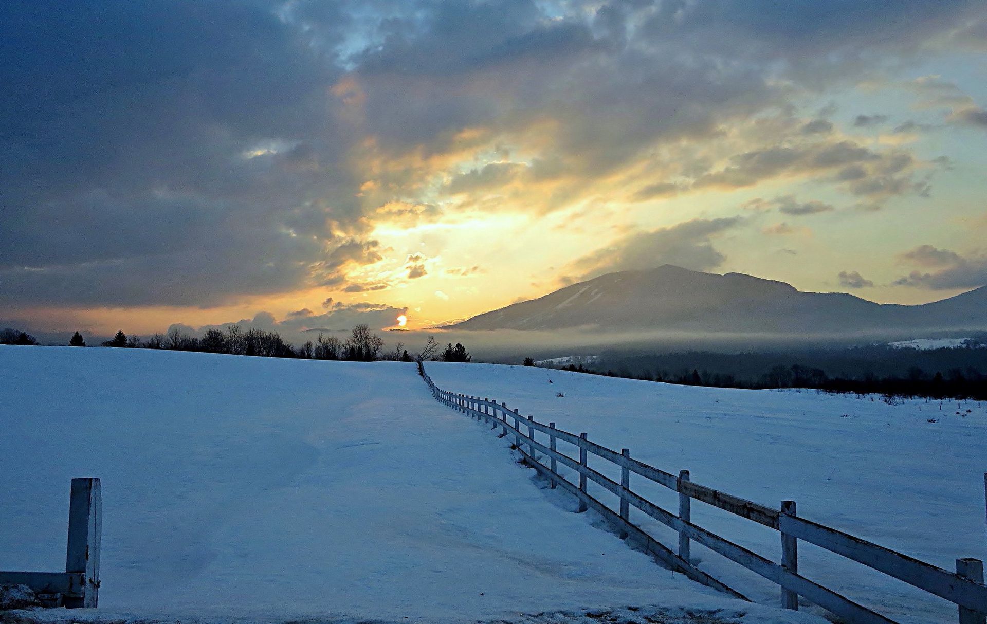Long fence in the snow with mountains in the background