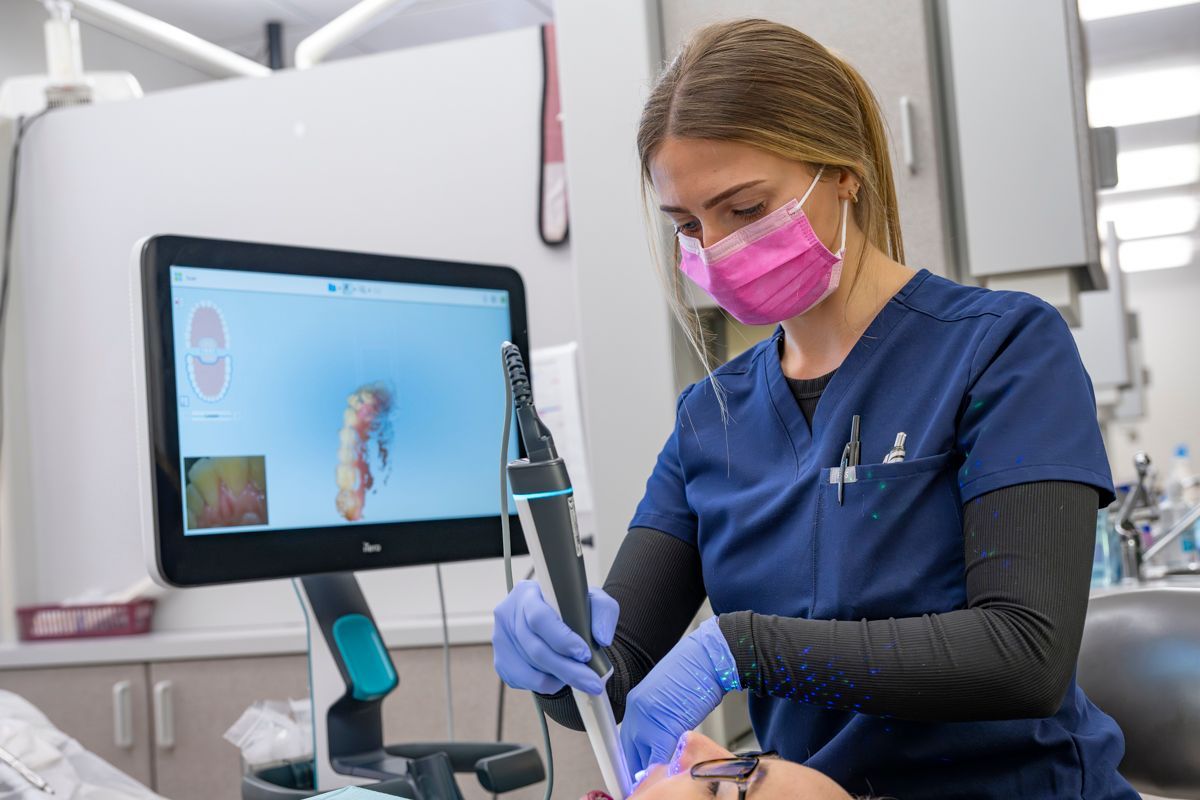 A female dentist is examining a patient 's teeth in a dental office near Wake Forest, NC.