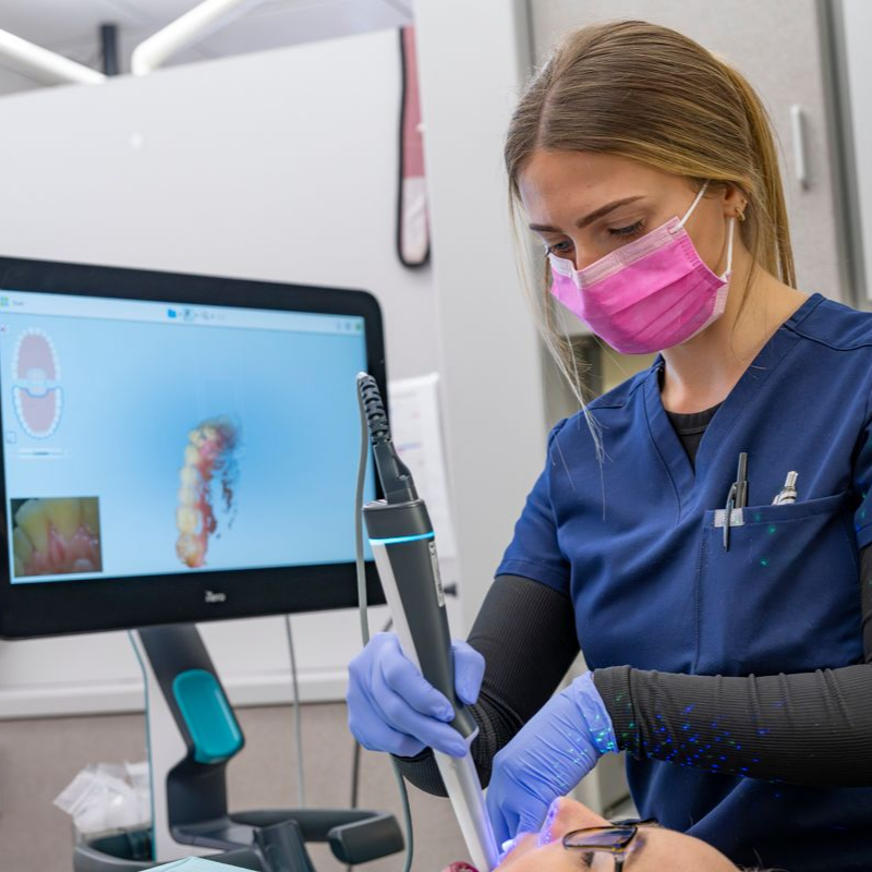 A female dentist is examining a patient 's teeth in a dental office near Garner, NC.