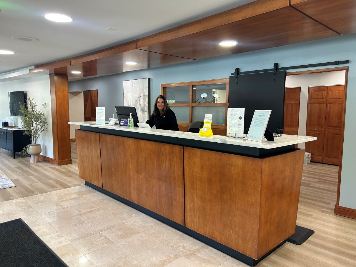 Modern hotel lobby with a wood reception desk and a staff member behind it in Raleigh NC