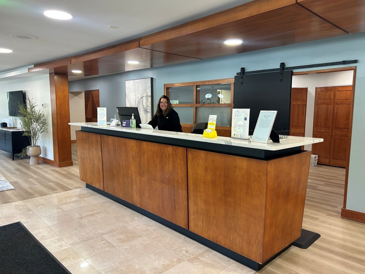 Lobby reception desk with a staff member behind a wood-and-stone counter in a modern interior in Raleigh NC.