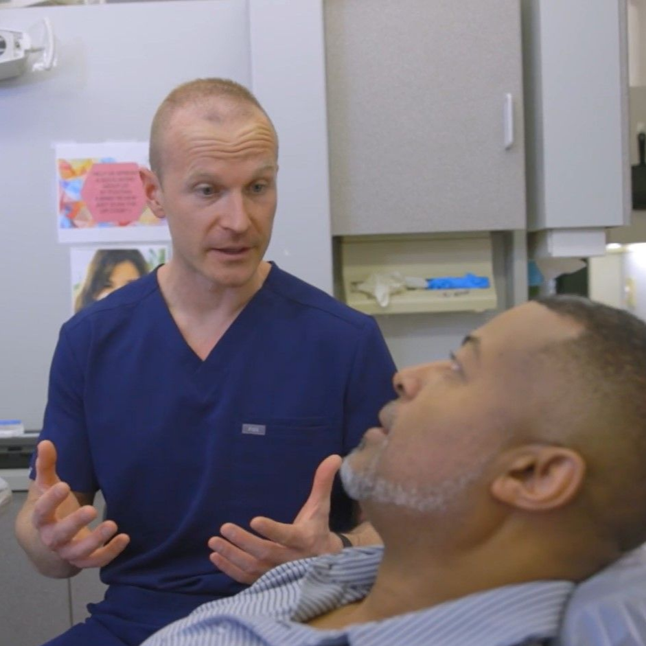 A man is sitting in a dental chair talking to a dentist near Knightdale, NC.