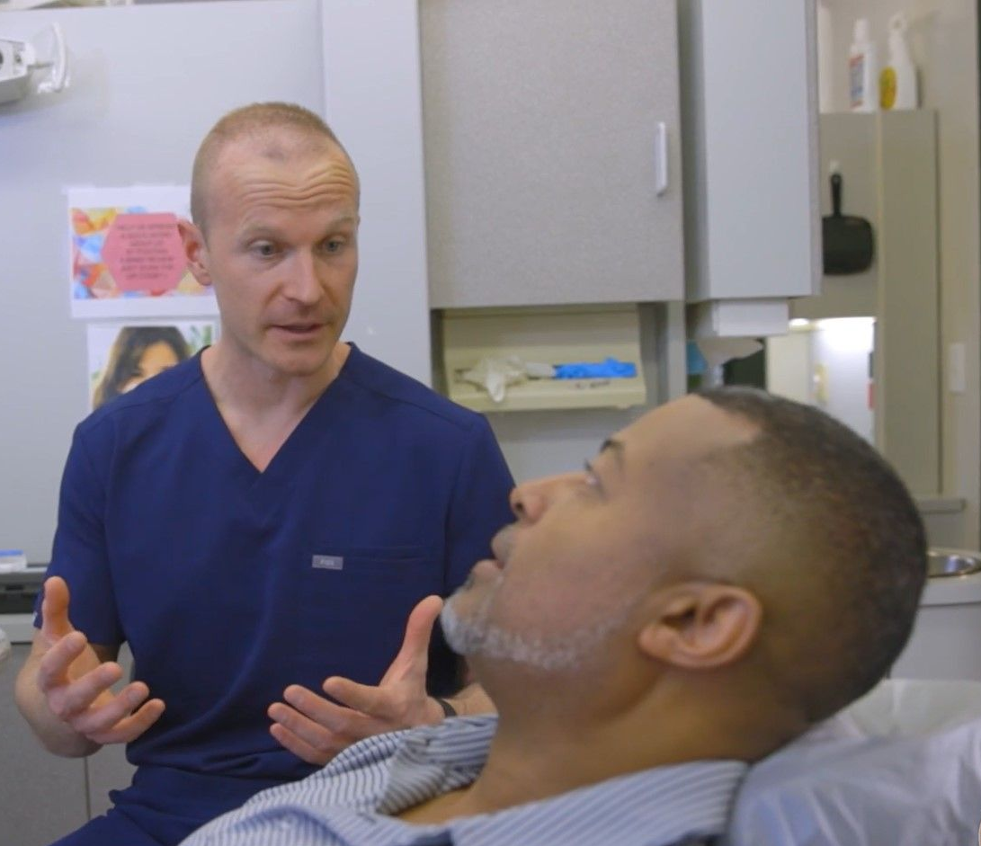 A man is sitting in a dental chair talking to a dentist near Garner, NC.