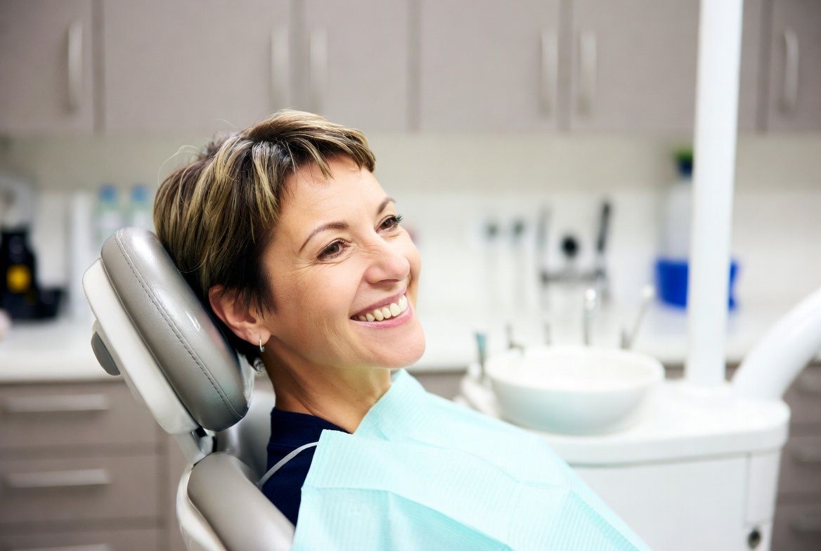 Smiling patient reclines in a dental chair in a bright clinic in Raleigh, NC.