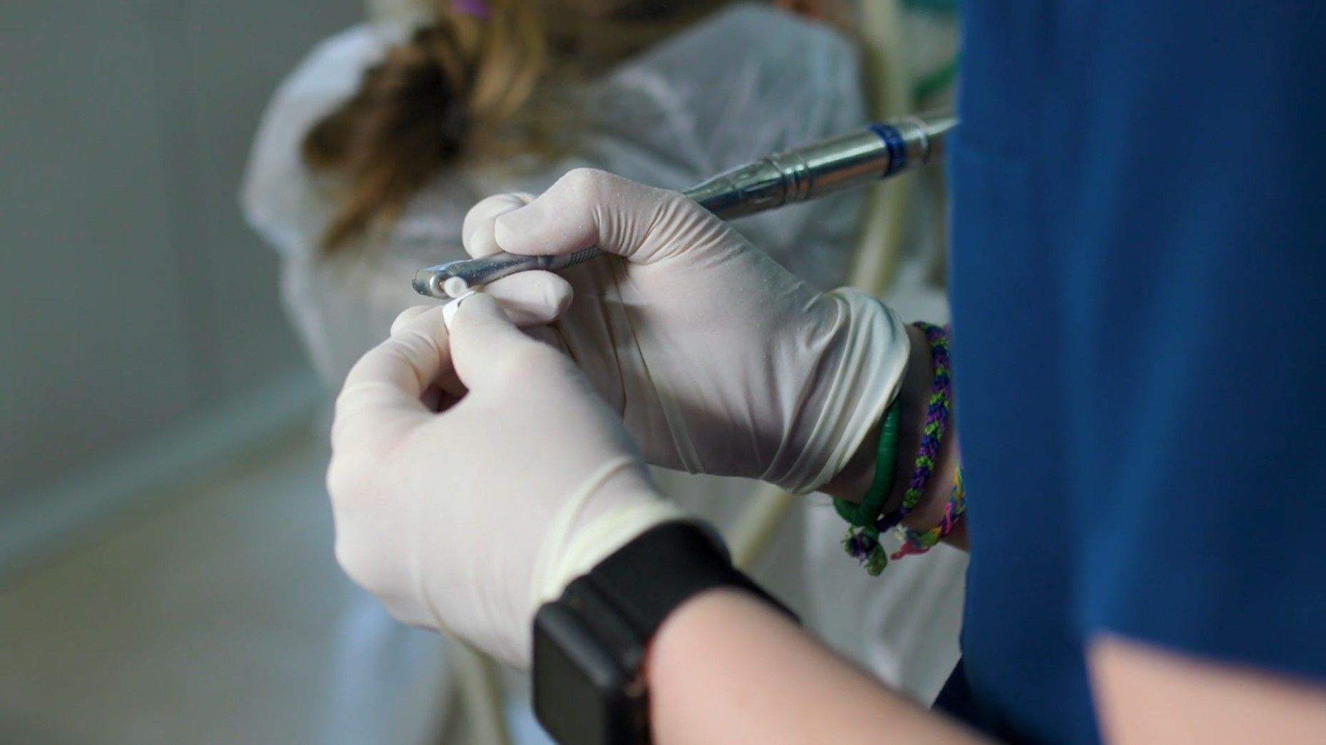 A dentist is using a drill on a patient 's teeth.