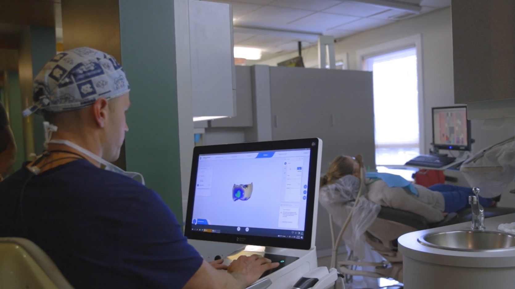 A dentist is using a computer in a dental office.