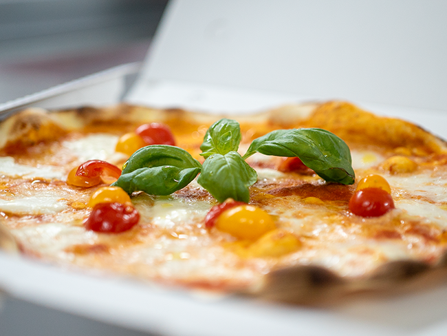 Un operaio con i guanti tiene in mano un sacchetto sigillato di impasto in un impianto di trasformazione alimentare.