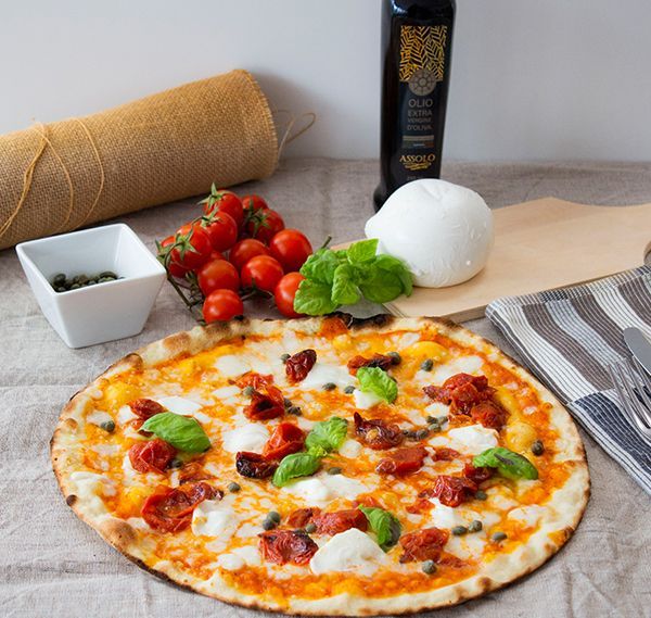 Pizza Margherita con pomodori, basilico, mozzarella e olio d'oliva su un bancone della cucina