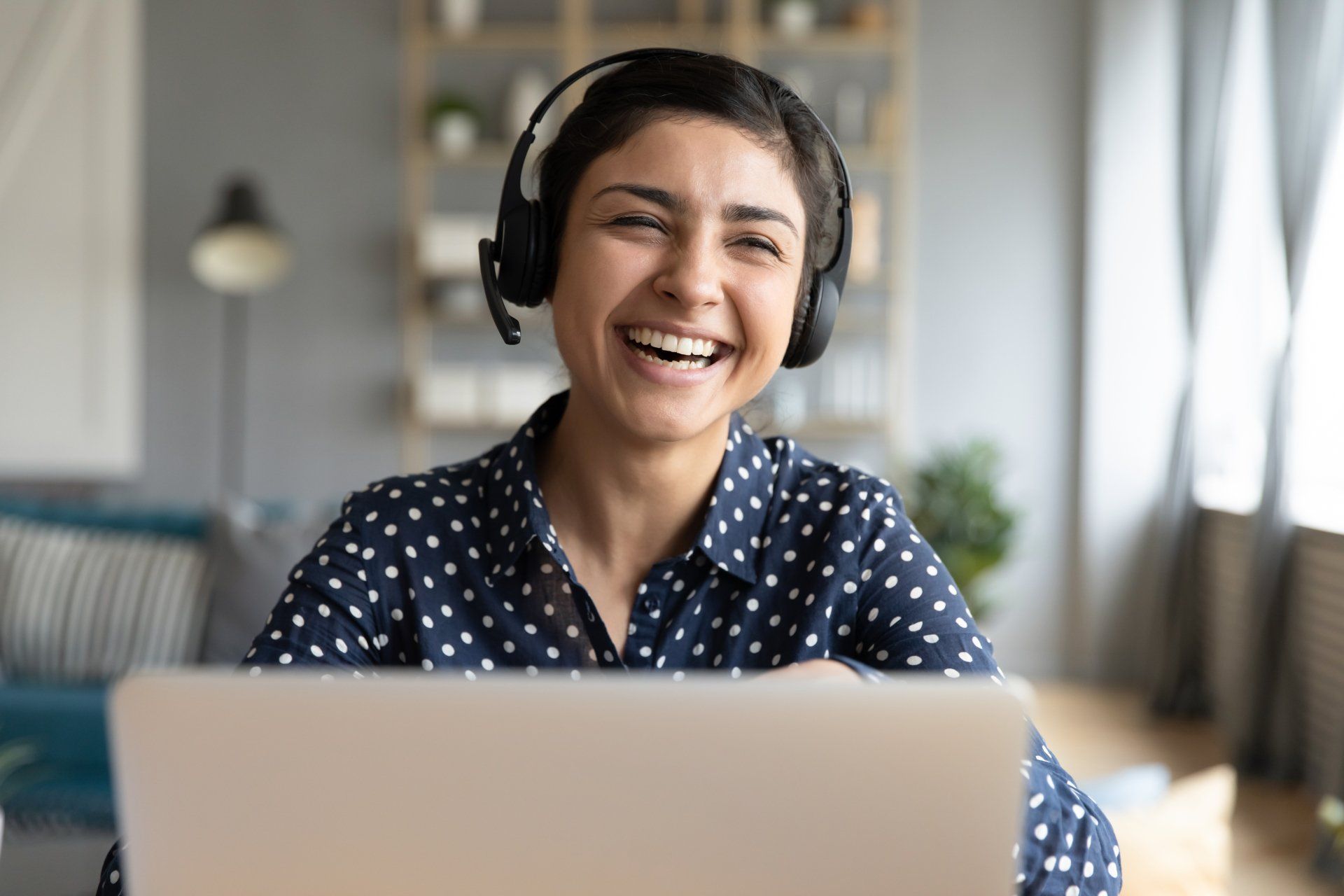 A woman wearing headphones is sitting in front of a laptop computer.